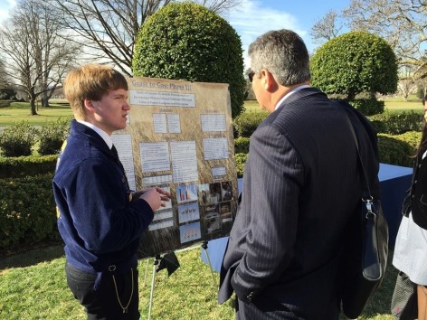 Iowa student shows off his research poster in the White House Rose Garden.