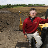 Dan Strey uses a bulldozer to clear space for new sports turf research
