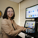 Su Jung Kim in her office with laptop and mobile phone