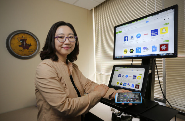Su Jung Kim in her office with laptop and mobile phone