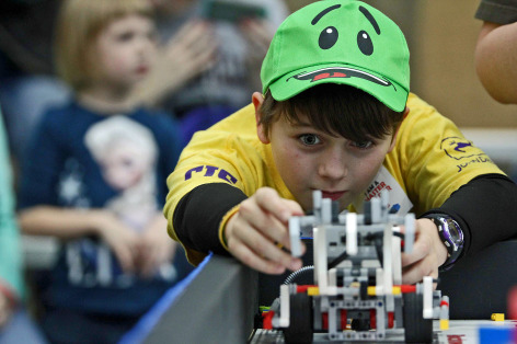 A student lines up his team's robot during FIRST LEGO League competition.