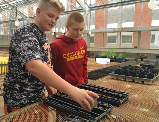 Ames High students Jake Schmit and Scott Junck work on a greenhouse experiment.