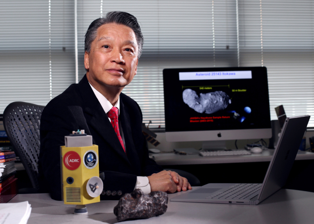 Bong Wie in his office with a model of his asteroid interceptor and a fragment from a meteorite.