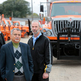 Iowa State researchers and DOT fleet manager stand near snow plow trucks