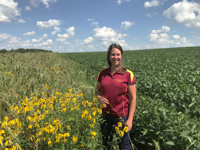 Lisa Schulte Moore stands in a farm field with prairie strips