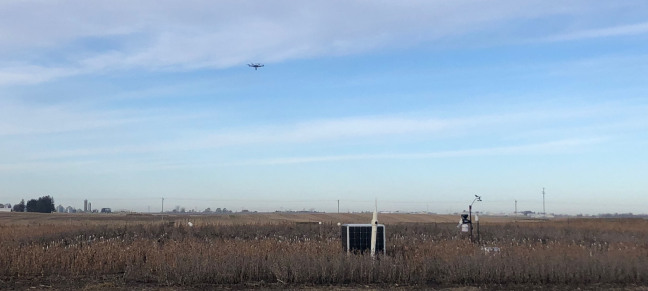 A drone aircraft hovering above a farm field
