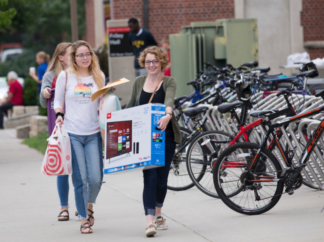 Shannon Kussatz, right, of Bettendorf, carries a TV while moving in her daughter, Isabelle, behind her, during move-in day at Friley Residence Hall at Iowa State University on Tuesday, August 15, 2017.