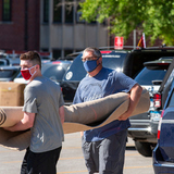 Two people carry a rolled up rug across a parking lot outside Friley Hall at Iowa State University, August 3, 2020. 