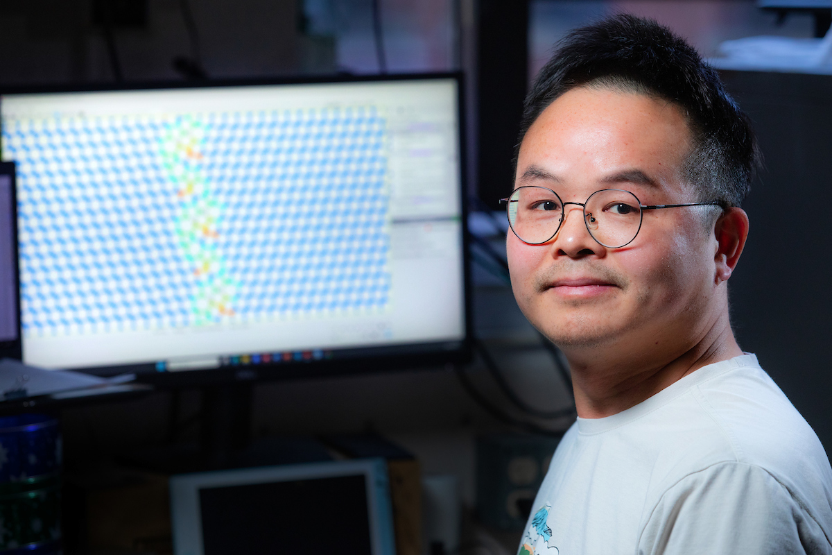 Kun Luo at a computer displaying an atomic model related to material studies of diamonds.