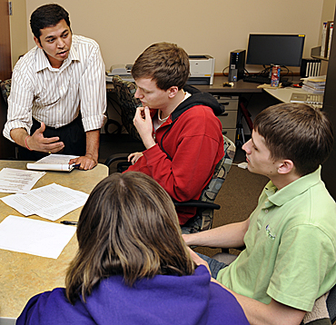 Abhijit Rao (standing), director of the College of Business Communication Center, and Tim Killian, one of the center's consultants, work with some students during a consulting session.