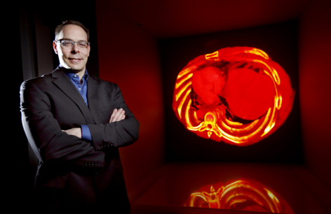 Eliot Winer in front of Iowa State's C6 virtual reality room with a medical application displayed