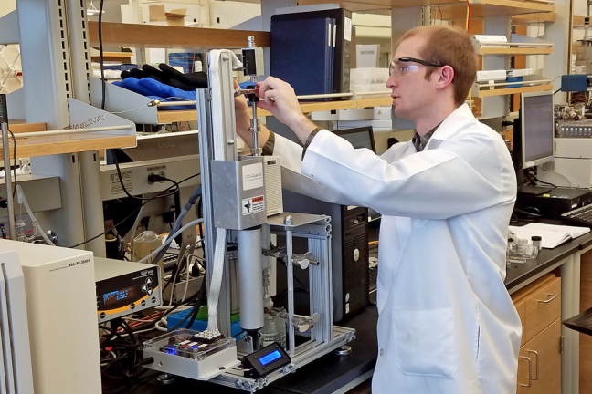 An Iowa State graduate student loads biomass into a micropyrolyzer.