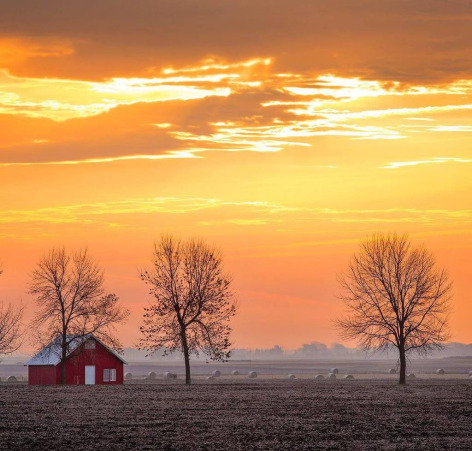 Sunrise in rural Iowa, includes a barn and hay bales