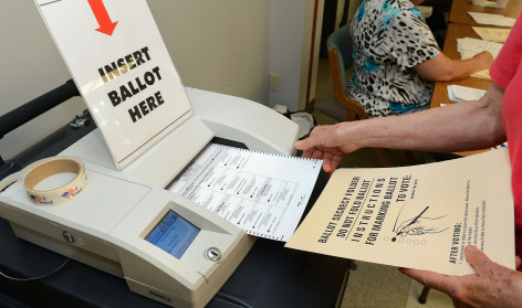 Voter placing ballot in machine