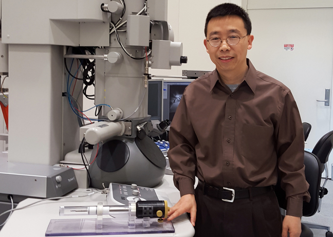 Xiaoli Tan with special specimen holder and a tramsmission electron microscope.
