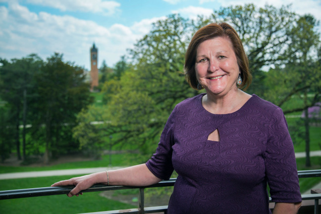 Dianne Bystrom standing on Catt Hall balcony with Campanile in background