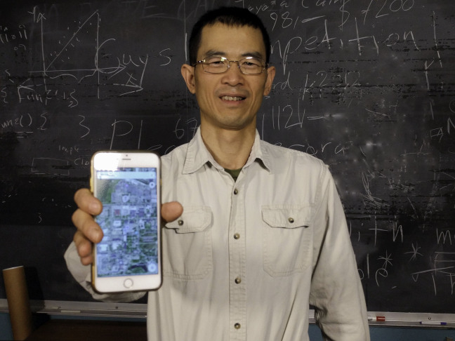 Ying Cai holding phone in his lab