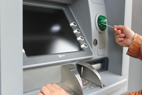 Person inserting debit card in ATM