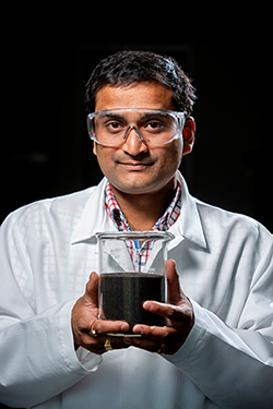 Santanu Bakshi holds a beaker of biochar.