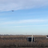 A drone aircraft hovering above a farm field