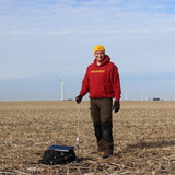 Bradley Miller takes soil samples with an instrument in the middle of a farm field