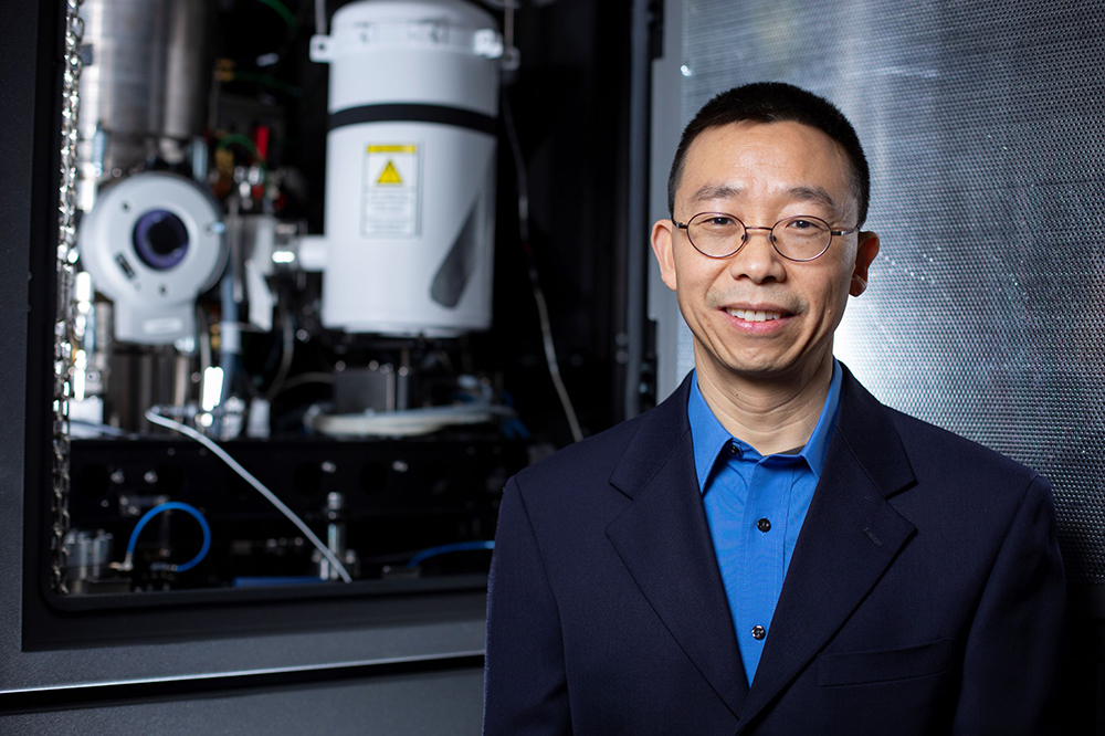 Iowa State's Xiaoli Tan stands before a transmission electron microscope at the Ames Laboratory's Sensitive Instrument Facility.
