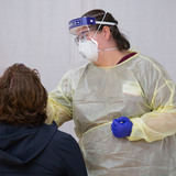 Health care worker in PPE administering COVID-19 test