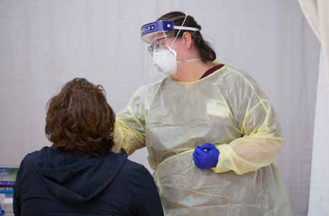 Health care worker in PPE administering COVID-19 test