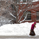 A woman walks past piles of snow on the ISU campus in February 2019.