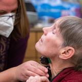 Associate Professor of Kinesiology Elizabeth Stegemoller attaches sensors to the throat of Kathy Gundlach, a study participant.