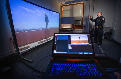 ISU Police Chief Michael Newton talks to the projected image on the VirTra-100 training simulator.