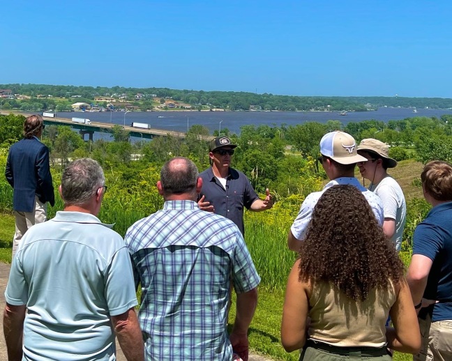 Project leader addressing crowd at river overlook