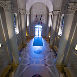 A photo of the Gold Star Hall at Iowa State University's Memorial Union. Gray stone pillars line the hall, and an American and Iowa flag stand against the far wall. The walls on the left and right are inscribed with the nemes of fallen veterans who are for