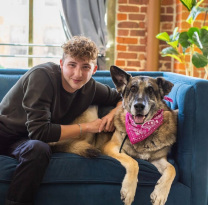 Matt Nelson sits on a sofa next to his dog, Doug