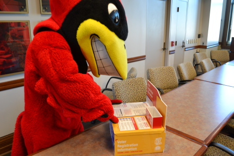 Cy reading a voter registration information box in Catt Hall at Iowa State.