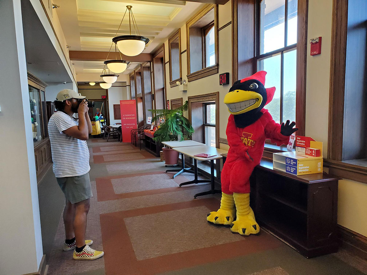 Demarquis Heard ('23 political science) takes a photo of Cy next to a voter registration information box in Catt Hall at Iowa State.