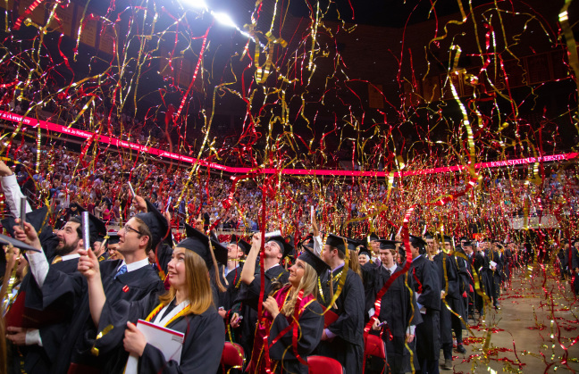 Cardinal and gold streamers falling from the ceiling inside Hilton Coliseum during commencement ceremony