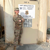 Birttany Whitehead stands in front of a military police building in Kuwait wearing army fatigues