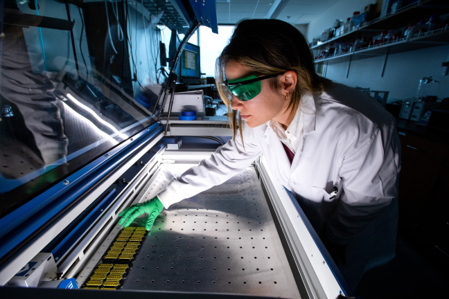 Raquel Rainier places circuit boards to be charred by a laser to create graphene