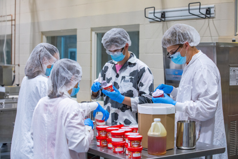 From left, ISU Creamery student employees Jennessa Sharratt, Hannah Even, Daniel Brumm and Drew Taylor package a new batch of Lunar Lavender ice cream in the Food Sciences Building. (Christopher Gannon/Iowa State University)