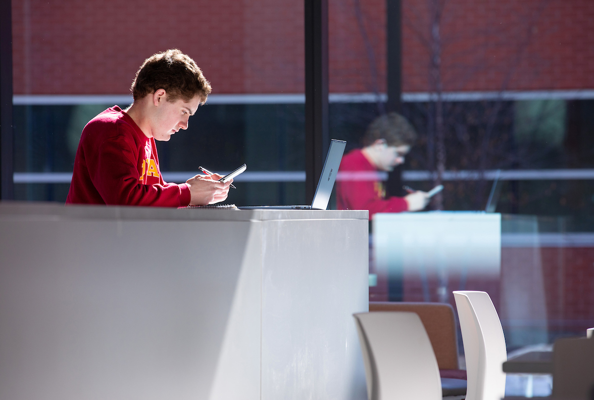 Freshman aerospace engineering major Collin Grota, of Sturgeon Bay, Wisc., soaks up some sunshine while looking at his phone in a newly-furnished study area in the southeast corner of the first floor of the Student Innovation Center. Photo by Christopher G