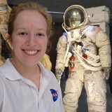 Sarah Stewart stands in front of a display of a NASA space suit at the Johnson Space Center in Houston