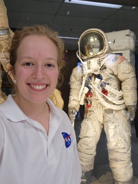 Sarah Stewart stands in front of a display of a NASA space suit at the Johnson Space Center in Houston