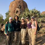 Iowa State professor Corinna Most posing with four students near a rock formation with babbons on it