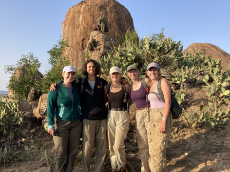 Iowa State professor Corinna Most posing with four students near a rock formation with babbons on it