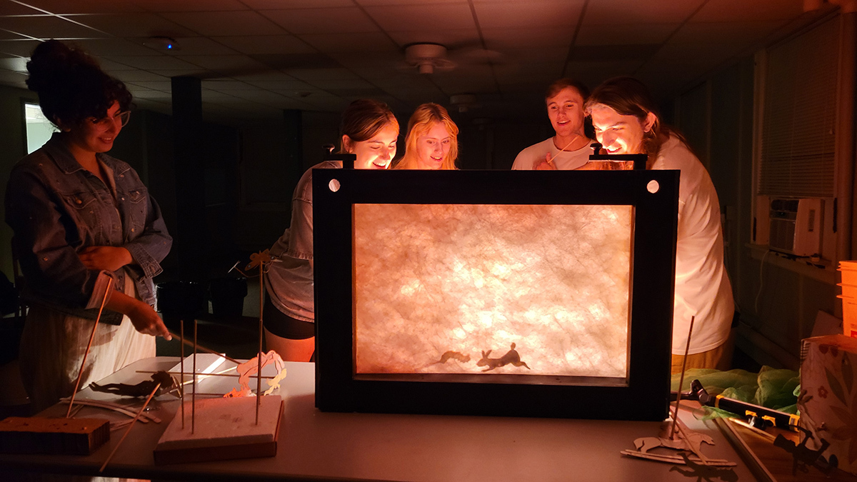 Student performers huddle around a "crankie," the back-drop for their shadow puppet performance of "The Velveteen Rabbit." Photo courtesy of ISU Theatre.