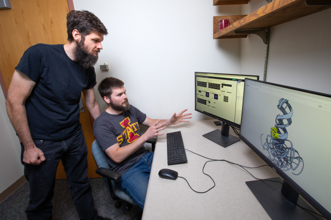 Walter Moss and grad student Jake Peterson look at an RNA molecule on a computer screen.