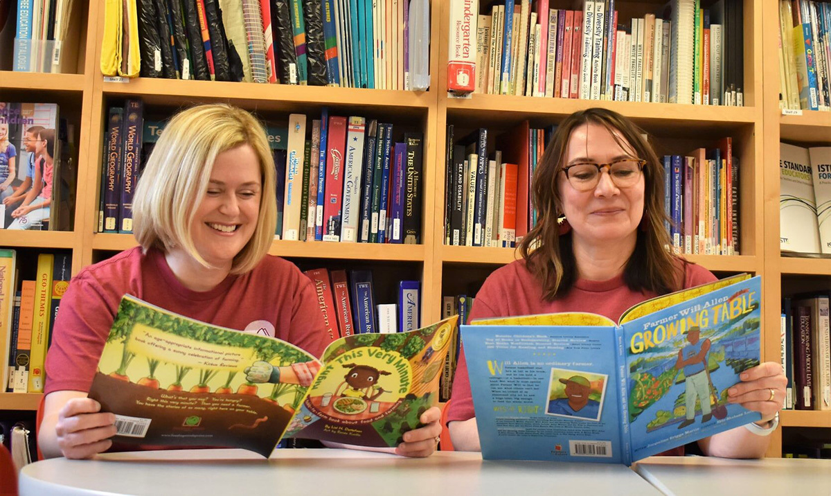 Sara Nelson, 4-H STEM specialist and director of the NASA Iowa Space Grant Consortium and NASA Iowa EPSCoR (left,) and Constance Beecher read children's books included in the Read Across America kits for 2022. Photo by Ryan Riley/Iowa State University.