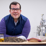 Nacu Hernandez wears safety goggles and leans over a table covered with asphalt samples at a laboratory in the ISU Research Park
