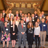 A large group of ISU students stands on the steps inside the Iowa Capitol
